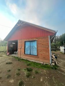 una pequeña casa con techo rojo en cabaña Wenu Mapu queule, en Queule