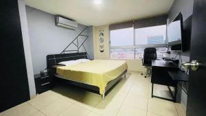 Five Stars Suites - Kennedy - Guayaquil في غواياكيل: غرفة نوم بسرير ومكتب ونافذة
