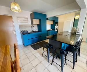 cocina con armarios azules, mesa y sillas en LA PLAYA - L'Appartement COZY - 2 à 5 personnes, en Sainte-Anne