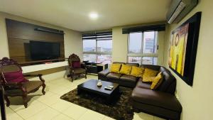 a living room with a couch and a tv at Five Stars Suites - Kennedy - Guayaquil in Guayaquil