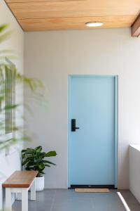 a blue door in a room with a wooden ceiling at The Elements l Water l 4 Stunning Apartments each with Private Outdoor Dining l Walk to the Beach l Pet Family and Event Friendly l Wifi l Netflix l Outdoor Shower l Communal BBQ Pavilion and Lawn Area l in Christies Beach