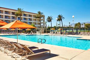 una piscina con sillas y sombrillas junto a un hotel en DoubleTree by Hilton Golf Resort Palm Springs, en Cathedral City