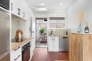 a kitchen with white cabinets and wood floors at The Elements l Water l 4 Stunning Apartments each with Private Outdoor Dining l Walk to the Beach l Pet Family and Event Friendly l Wifi l Netflix l Outdoor Shower l Communal BBQ Pavilion and Lawn Area l in Christies Beach