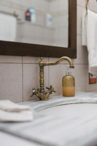 a bathroom sink with a brass faucet and a soap bottle at Billiard Home in Trikala in Tríkala
