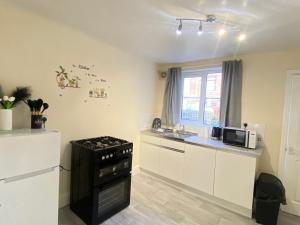 Una cocina con gabinetes blancos y una estufa negra. en Kisobi Home Bedroom 2, en Hull