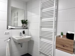 a white bathroom with a sink and a mirror at Modernes Apartment inkl. TG-Stellplatz in der Nähe zum Bahnhof - YUKA Apartments in Schwäbisch Hall +6 photos