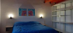 - une chambre avec un lit bleu et 2 fenêtres dans l'établissement Los Cactus, à Tafí del Valle