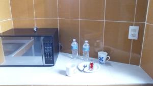 - un four micro-ondes sur un comptoir avec 2 bouteilles d'eau et des tasses dans l'établissement The green house by E&M dos camas matrimoniales, à Mexico
