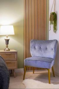 uma cadeira azul sentada num quarto ao lado de uma mesa em Broughton House with Free Parking, Balcony, Fast Wifi and Smart TV with Netflix by Yoko Property em Milton Keynes