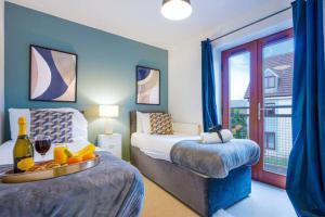 米爾頓凱恩斯的住宿－Broughton House with Free Parking, Balcony, Fast Wifi and Smart TV with Netflix by Yoko Property，一间卧室设有两张带蓝色墙壁和窗户的床。