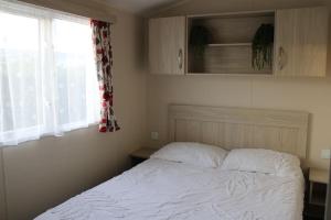 1 dormitorio con 1 cama blanca y ventana en Cosy beachfront getaway in Mersea, en West Mersea