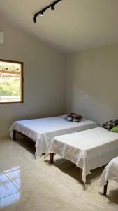 Duas camas num quarto branco com uma janela em Chalé da Picareta em São Roque de Minas