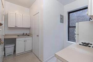 kuchnia z białymi szafkami, umywalką i oknem w obiekcie The Upper East Side Monthly Rentals Apartments w Nowym Jorku