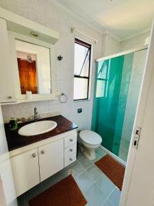 uma casa de banho com um lavatório, um WC e uma cabina de duche em vidro. em Lindo Apartamento Vista mar Portaria 24h Piscina e Lazer no Guarujá