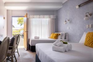 a bedroom with two beds with chairs and a window at South Pacific Palms Motor Inn in Tuncurry