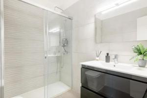 a white bathroom with a shower and a sink at SantaRooms in Santa Cruz de Tenerife