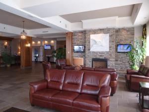 a lobby with leather furniture and a fireplace at Hotel L'Oie des neiges in Lévis
