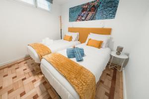 ヴィラ・ノヴァ・デ・ガイアにあるDouro Garden & Rooftop - Authentic Portuguese Guesthouseの白い壁とウッドフロアの客室で、ベッド2台が備わります。