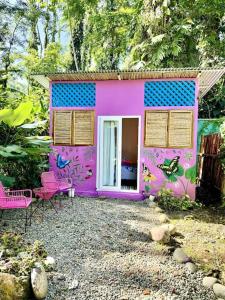 a purple house with chairs and a table in front of it at Casa Mariposa in Puerto Viejo