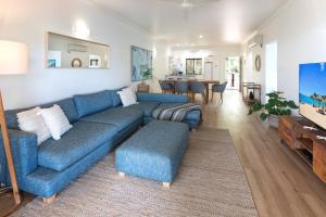 a living room with a blue couch and a dining room at Compass Point on Hamilton Island by HIHA in Hamilton Island