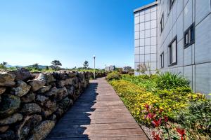 uma passagem ao lado de uma parede de pedra ao lado de um edifício em Mulddeule Shimpang Resort em Jeju