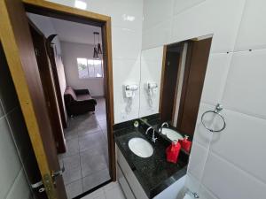 a bathroom with a sink and a mirror at Apartamento 2 Quartos Bertioga WVM in Bertioga