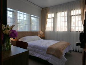 a bedroom with a bed with windows and a table at Floralia Casa Boutique in Bogotá