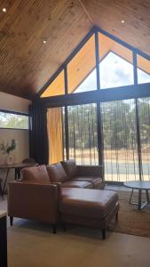 a living room with a leather couch in front of windows at Chalet Hills in Sampsons Flat