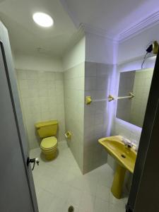 baño con aseo amarillo y lavamanos en Rustik House, en Medellín