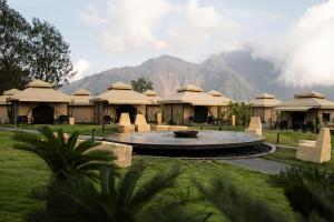 un grupo de cabañas con montañas en el fondo en Toteme Glamping and Hot Spring Kintamani en Kintamani