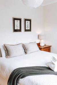 1 dormitorio con 1 cama blanca y 2 cuadros en la pared en 'Sealladh Beinne', Coastal Haven, en Falmouth