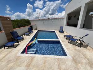 a swimming pool on a patio with chairs at Casa 2 Chalé Alto dos Bandeirantes-Tiradentes in Tiradentes