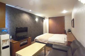 a small hotel room with a bed and a television at ホテル タイムレス 明石 男塾ホテルグループ in Akashi