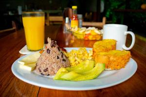 a plate of breakfast food on a table with a glass of orange juice at Arenal Descanso in Fortuna
