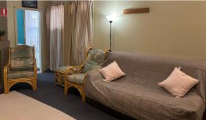 a living room with a couch and two chairs at Broken Hill Tourist Lodge in Broken Hill