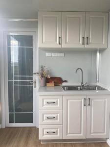una cocina con armarios blancos y fregadero en Beachside Bungalows, en Batemans Bay