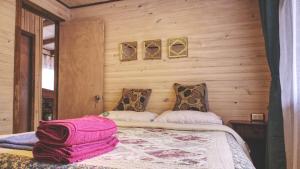 1 dormitorio con 1 cama en una pared de madera en Cabaña Los Coihues, en Puerto Montt