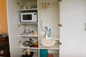 a kitchen pantry with a microwave and a shelf at St Kilda Studio in Cambridge
