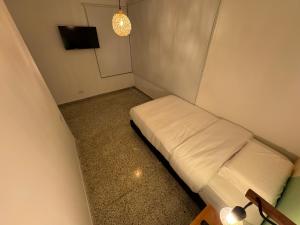 a small room with a white bed in a corner at Rustik House in Medellín