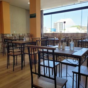 um restaurante com mesas e cadeiras e uma grande janela em Pousada Benedicta em Aparecida