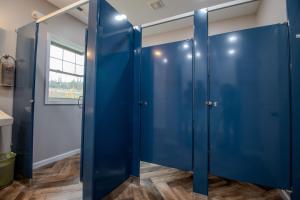 a row of blue doors in a bathroom with a window at The Lazy Tiger Hostel in Woodfin