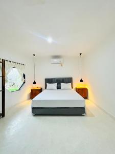 a white bedroom with a bed and two night stands at Surfers Beachfront Lombok in Kuta Lombok