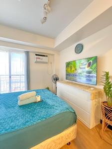 een slaapkamer met een bed en een tv aan de muur bij Celandine Minimalist Condo Staycation in Balintawak Quezon City in Manilla