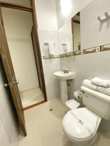 Baño blanco con aseo y lavamanos en Hotel San Julian, en Buga