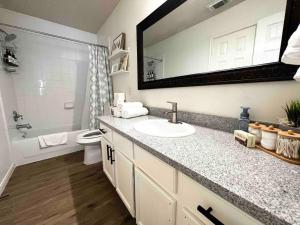 ein Badezimmer mit einem Waschbecken, einem WC und einem Spiegel in der Unterkunft Entire residential home - 1 story, 3 beds, 2 baths in Houston