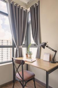 Un escritorio con una silla frente a una ventana con cortinas. en Roomio De Capella - Share Apartment, en Ho Chi Minh