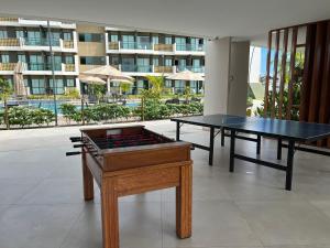 two ping pong tables in a room with a building at Flat Mana Beach Pono 216 na Praia de Muro alto in Ipojuca