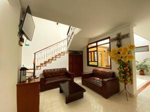 Sala de estar con 2 sofás de cuero y TV en Hotel San Julian, en Buga
