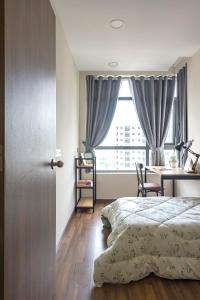 um quarto com uma cama, uma secretária e uma janela em Roomio De Capella - Share Apartment em Ho Chi Minh