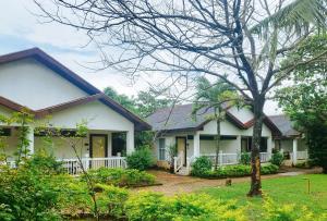 ein weißes Haus mit einem Baum davor in der Unterkunft RedDoorz @ Padi Beach Resort Oton Iloilo in Oton